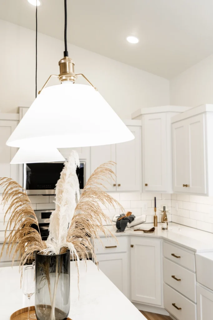 Modern kitchen featuring white cabinetry, a stylish pendant light, and a decorative vase with pampas grass, highlighting Paragon Homes' custom design aesthetic.