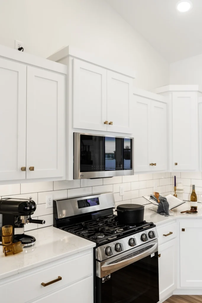 Modern kitchen featuring white cabinetry, stainless steel appliances, gas stove, and stylish decor, showcasing Paragon Homes' custom home design capabilities.