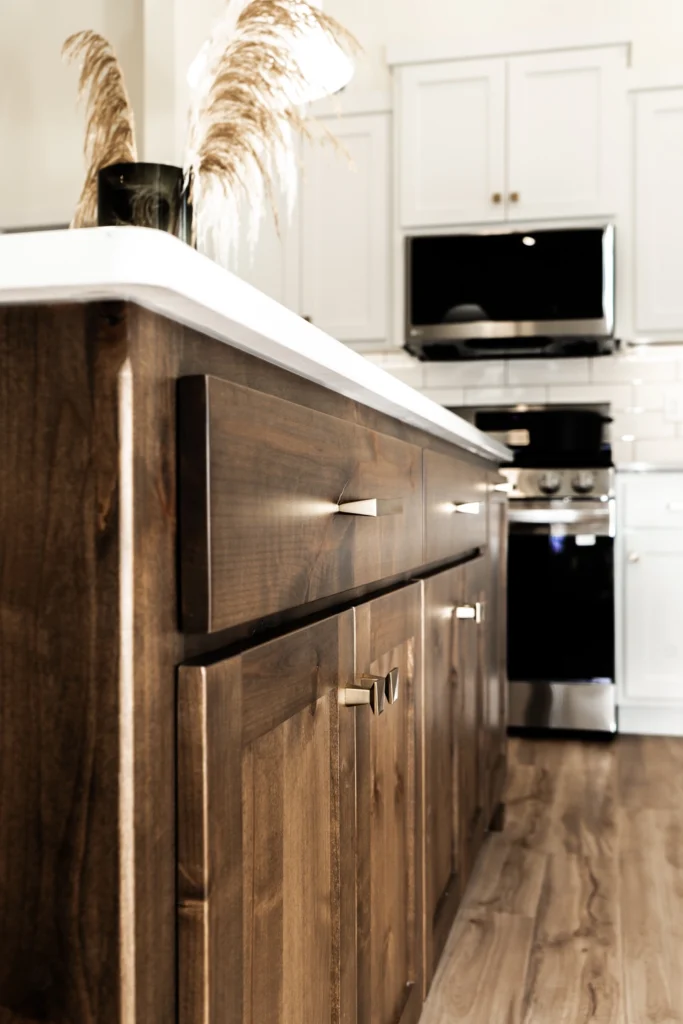 Modern kitchen with wooden cabinetry, sleek hardware, and decorative dried plants, showcasing custom home design by Paragon Homes in Fargo-Moorhead area.
