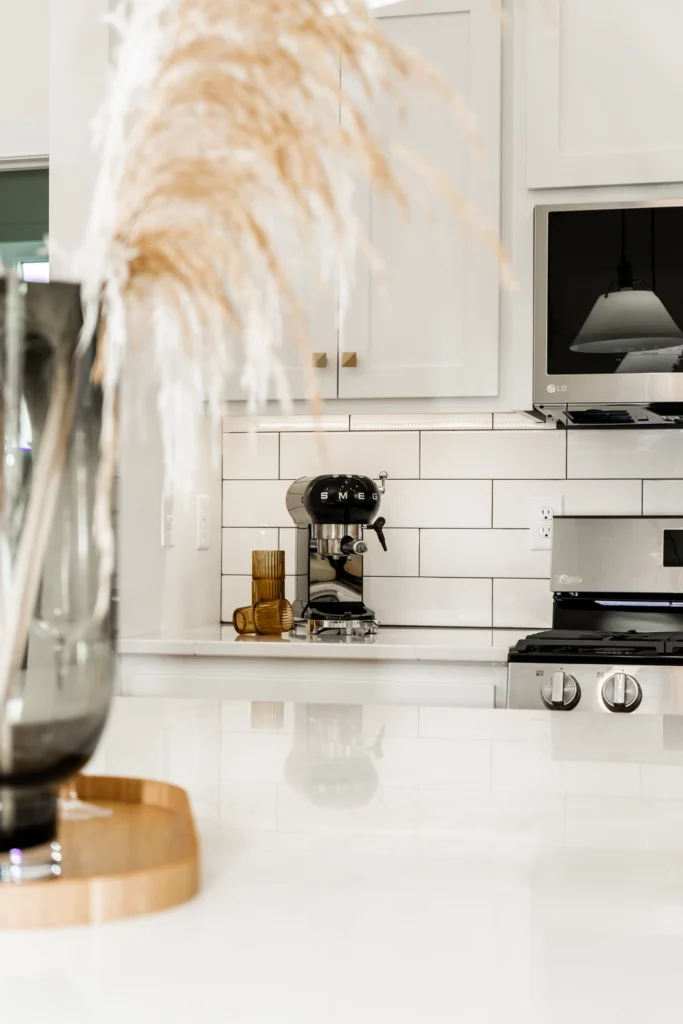 Modern kitchen interior featuring a sleek SMEG espresso machine, polished countertops, and stylish decor elements like a glass vase and decorative glasses, emphasizing Paragon Homes' custom home design aesthetic.