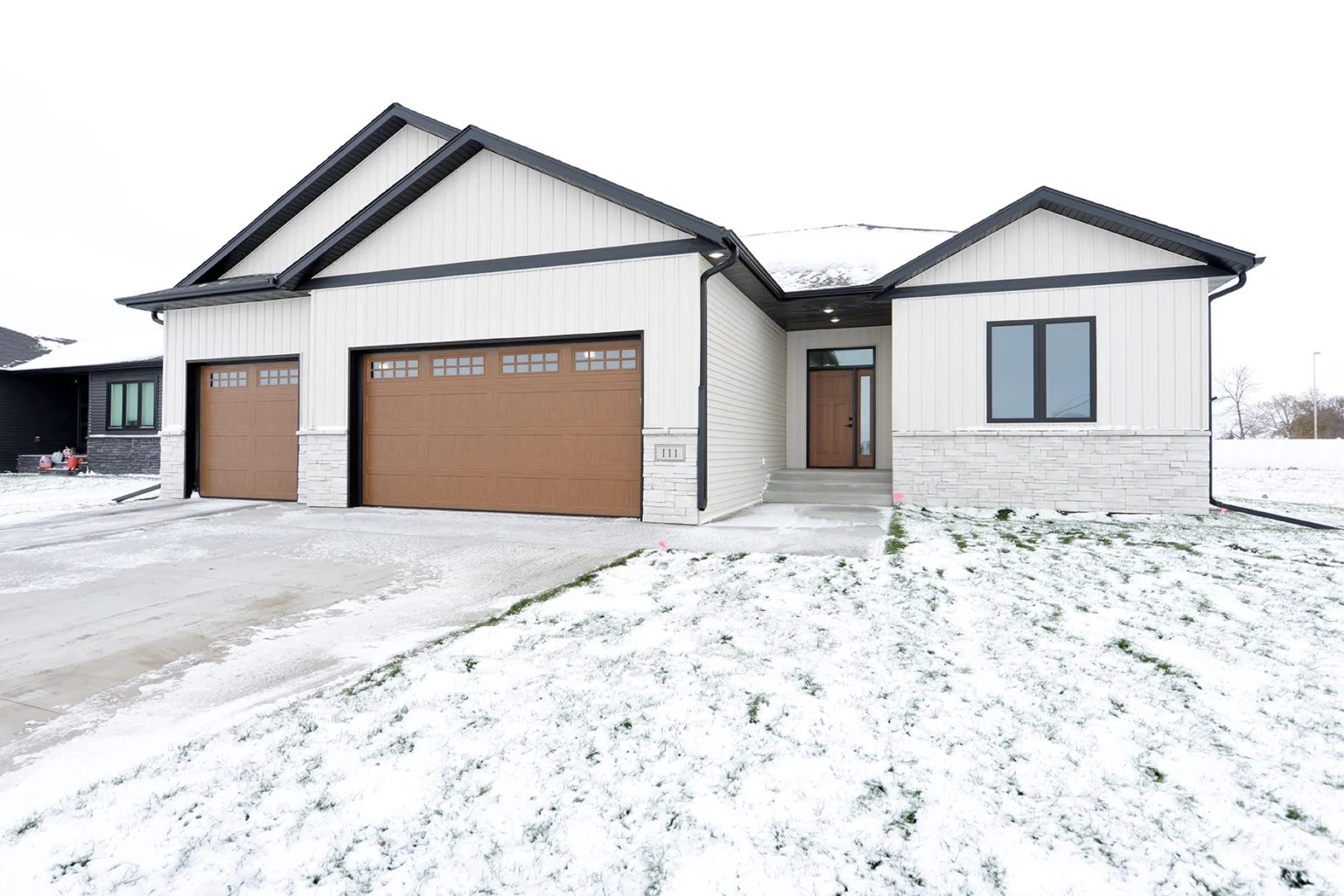 Custom home exterior in Davenport, ND featuring modern design, brown garage doors, and snow-covered lawn, showcasing Paragon Homes' craftsmanship.